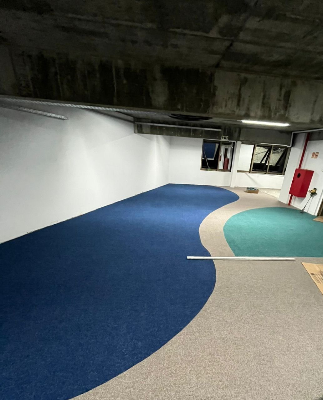 Carpete com desenho ondulado em azul, bege e verde em área comercial