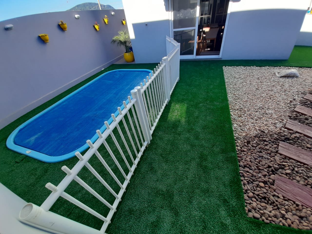 Grama sintética em área de piscina com deck e seixos