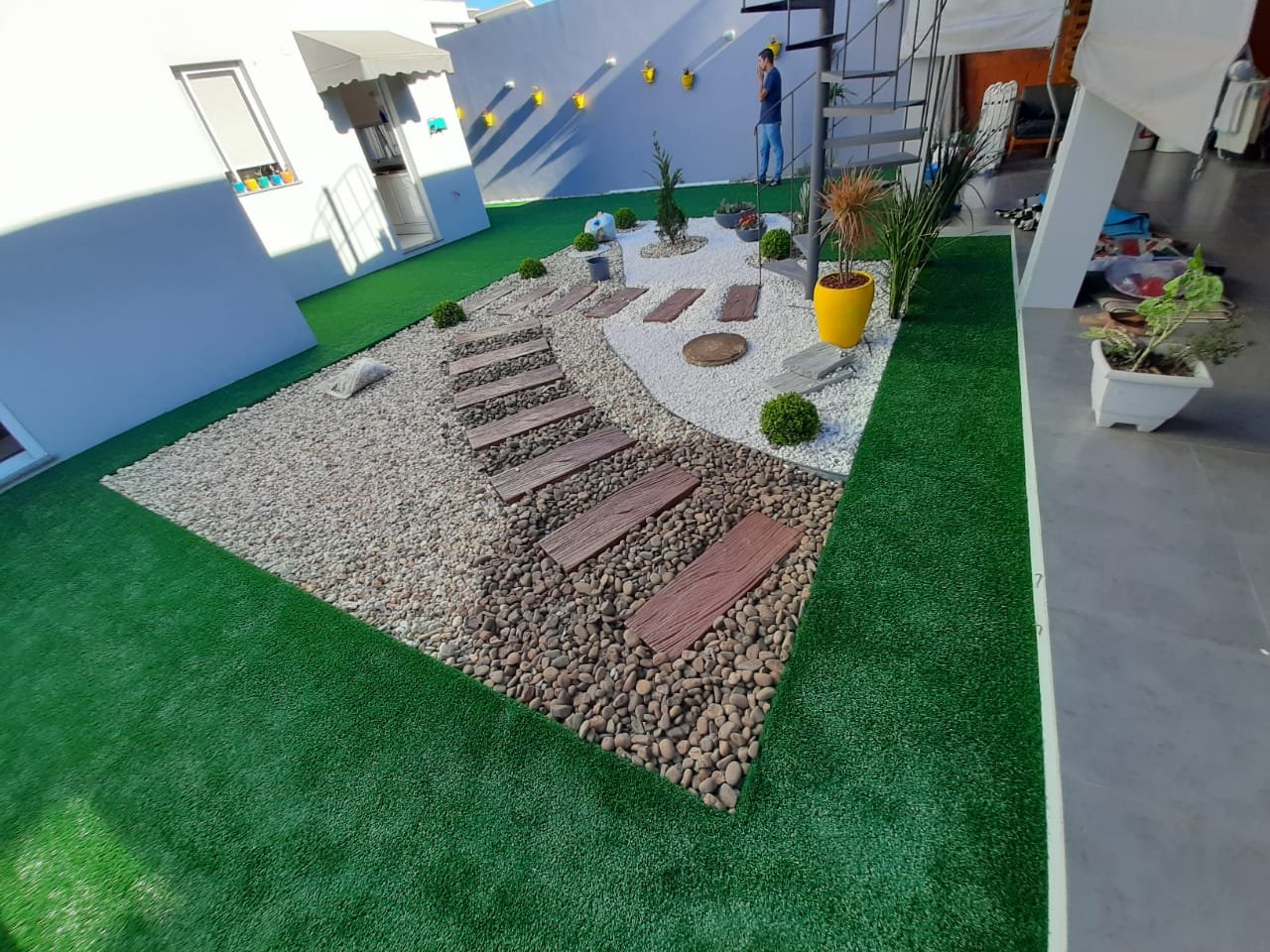 Grama sintética em jardim com escada de pedra e vasos