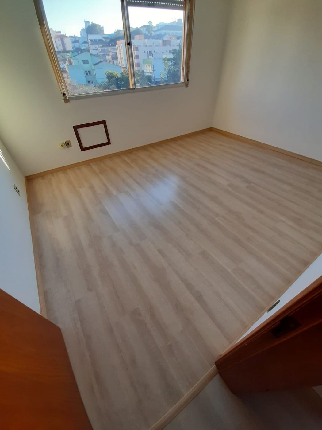 Piso laminado amadeirado claro em quarto — instalado pela DecorandoBem, Santa Maria