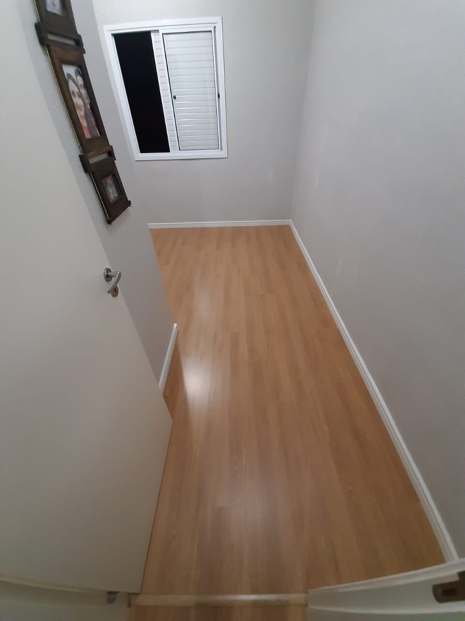 Piso laminado claro em quarto com rodapé branco