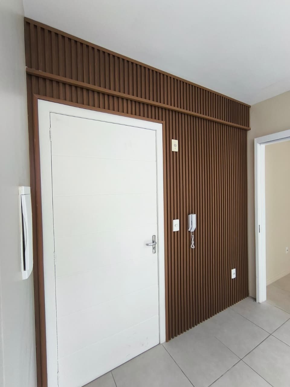Ripado de PVC escuro na parede da porta de entrada